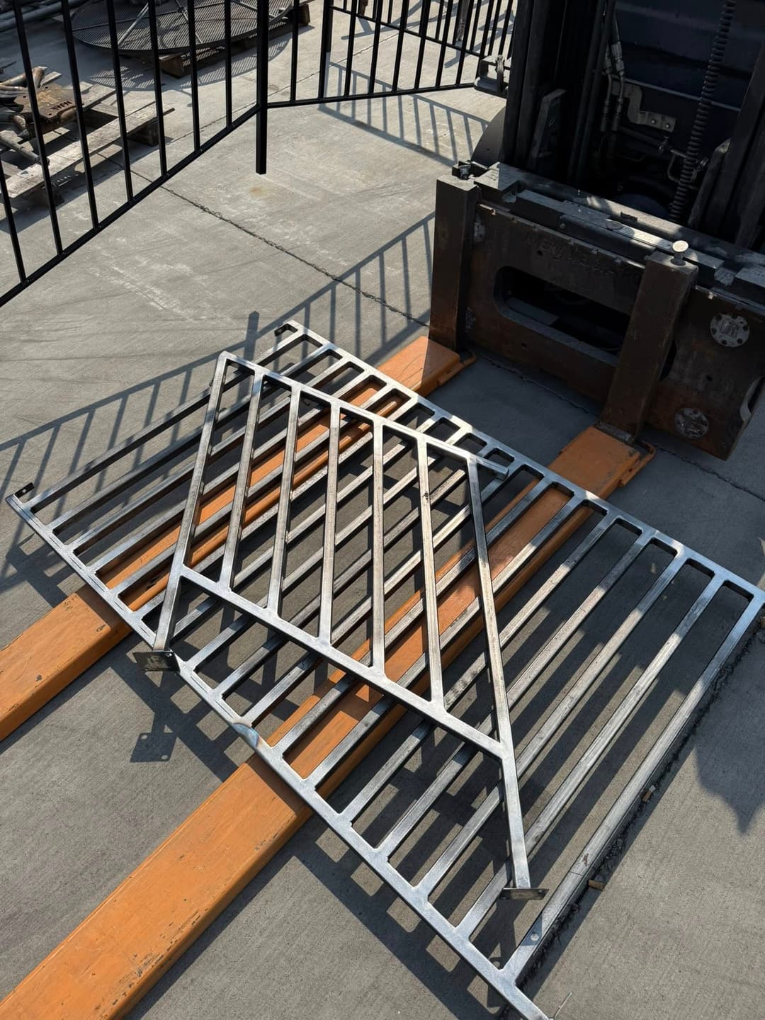 Metal ramp placed on wooden pallets near a forklift on a construction site.