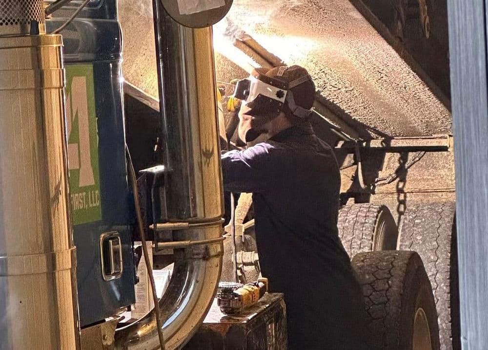 Mechanic performing maintenance on a truck, focused on repairs and equipment.